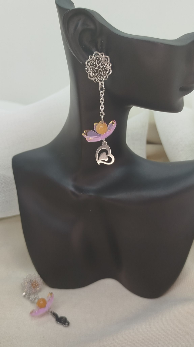 Clous d'oreilles fleur en acier inoxydable, ornés d'une fleur acrylique avec perle naturelle, et pendentifs "cœur" et "clé de sol" en acier.