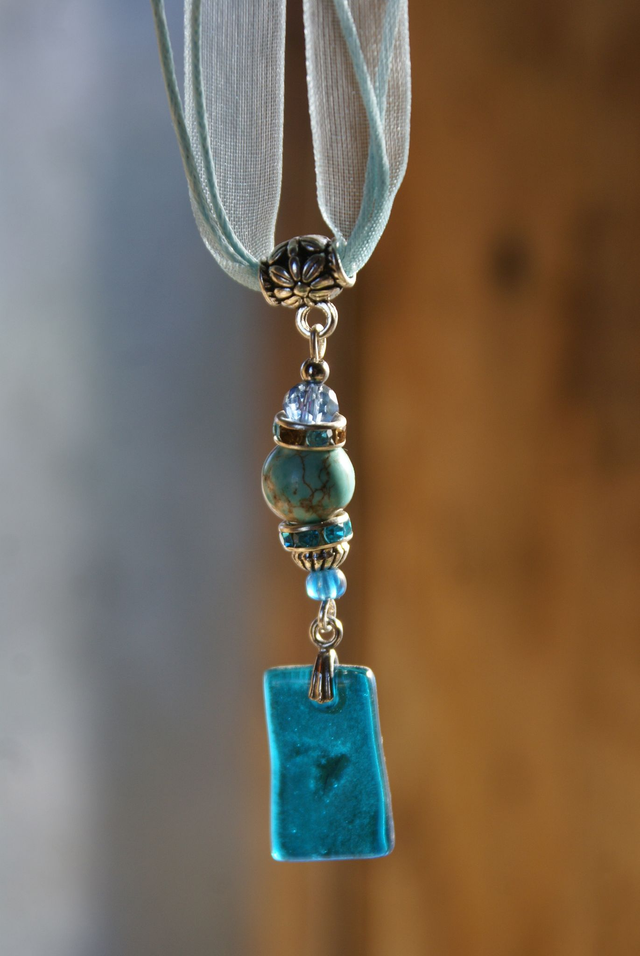 Pendentif en verre bleu turquoise et chaîne en coton bleu.