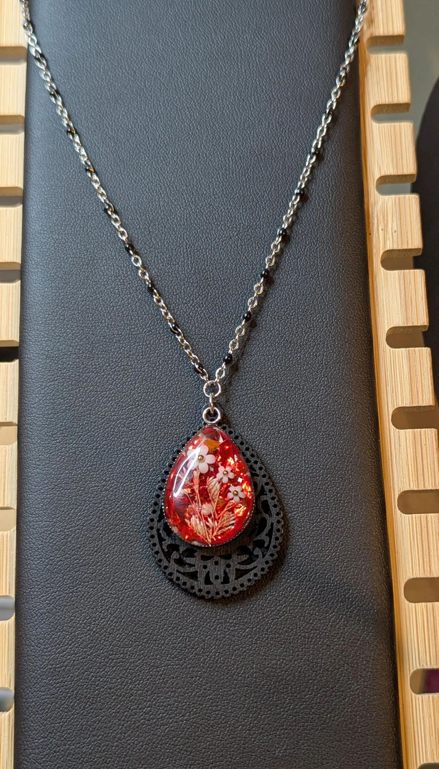 Collier sautoir long avec un pendentif en bois noir et un pendentif en résine rouge, fleurs blanche, chaine en argent. 