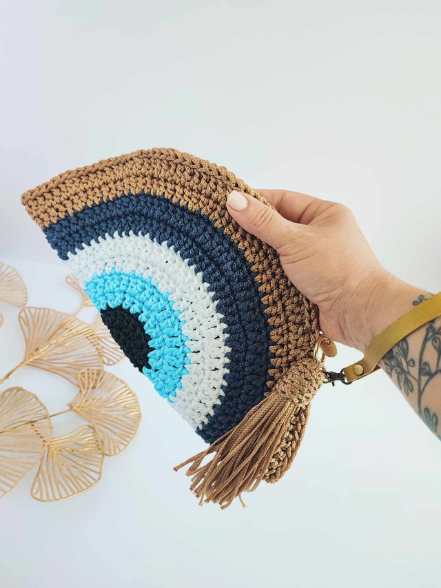 Sac Clutch mauvais œil fait main en crochet, pochette Nazar avec dragonne dorée, fermeture zippée et pompon – accessoire artisanal en polyester