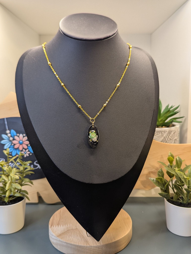 Collier mi long avec une chaine de couleur argent et un pendentif en résine noire avec des fleurs séchés. 