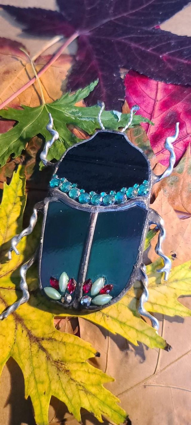 Scarabée en verre, au corps vert iridescent et à la tête noire, en Tiffany et monté en broche. 