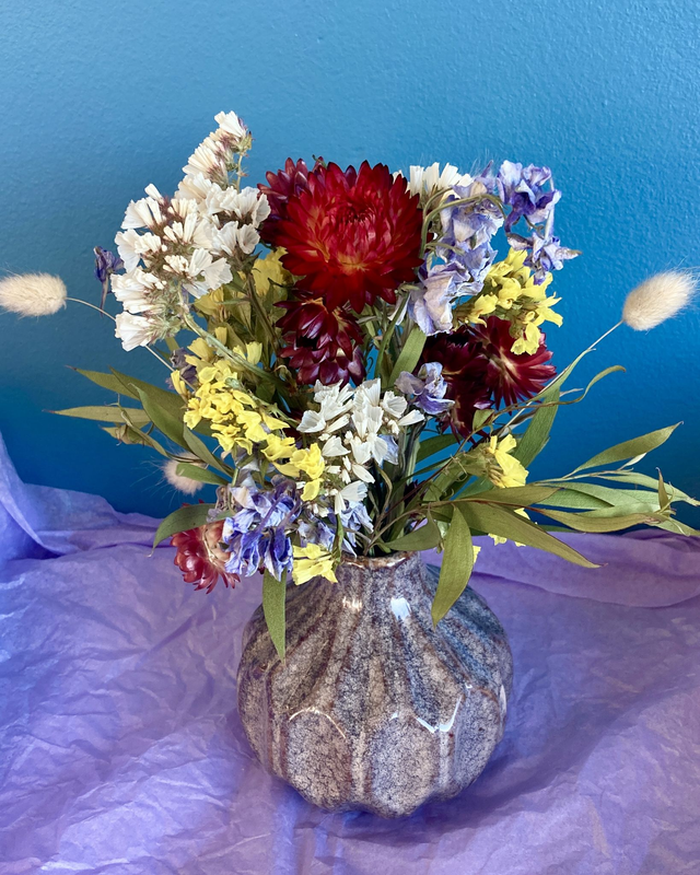 Local dried flower arrangement in mottled grey glazed vase 