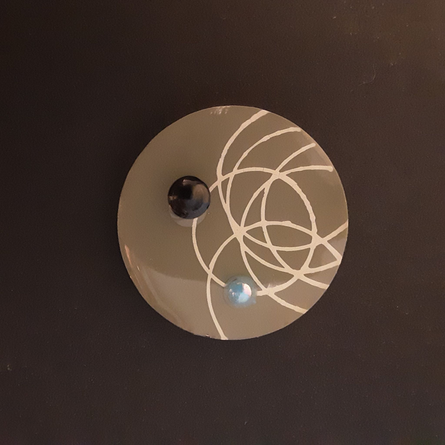 Broche ronde collection Ethnique fond mastic cercle beige et cabochon noir et bleu nacré