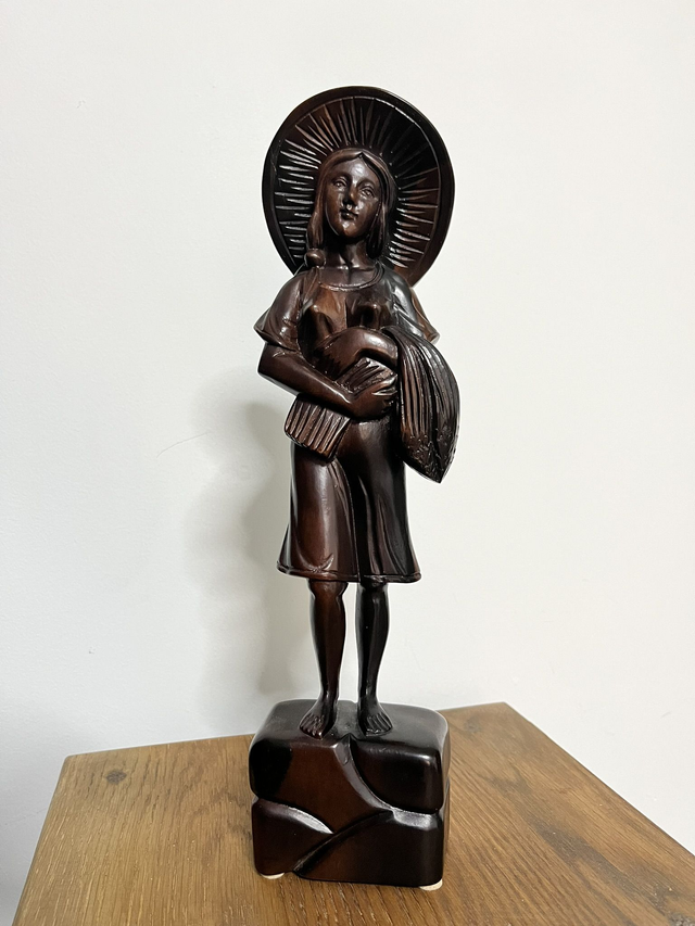 Wooden statue of a Filipino female farmer, with a hat, holding harvested rice.