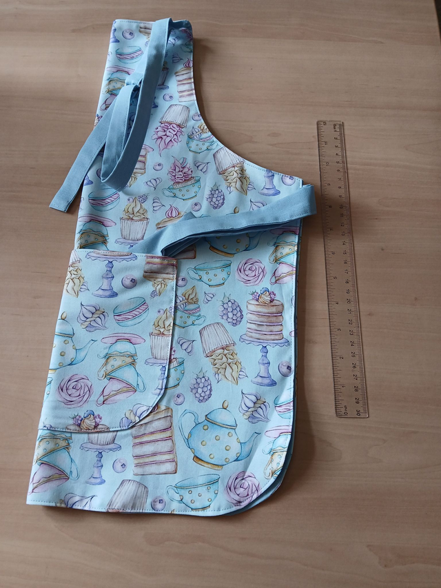 Childs Kitchen/Play Apron Three Wishes Frosted Fancies Cotton Fabric with lined Front pocket and pale blue lining.