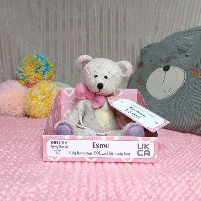 Esme. Small size, handmade teddy bear. UKCA. Tray base packaging. Standard Wool Felt. Traditional beige. Pink. Purple. Yellow.