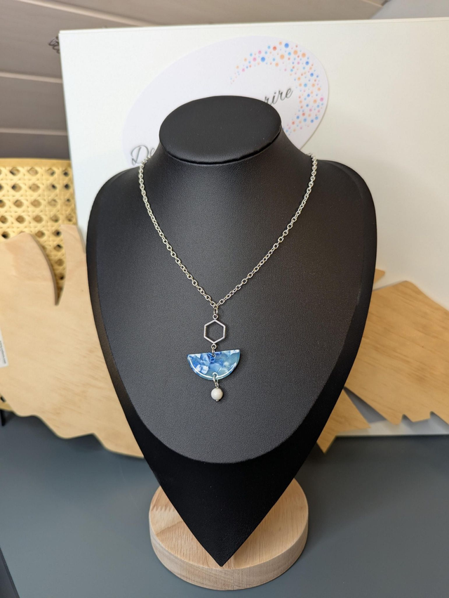 Collier mi long avec une chaine de couleur argent et un pendentif en résine bleu et blanc, et un pendentif en métal argenté. 