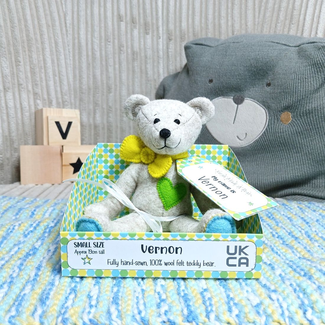 Vernon. Small size, handmade teddy bear. UKCA. Tray base packaging. Standard Wool Felt. Beige. Bright yellow, blue & green.