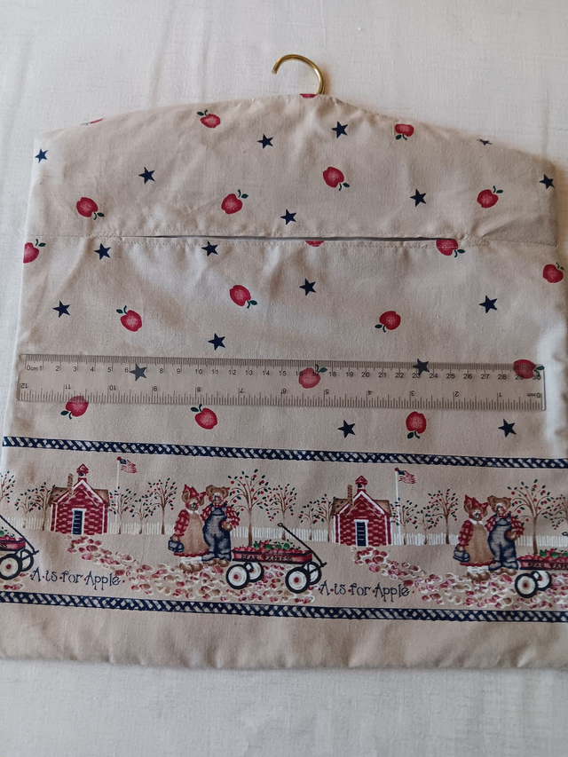 Hand made Peg Bag with wooden coat hanger. Apples print fabric with a picture border and plain beige lining.