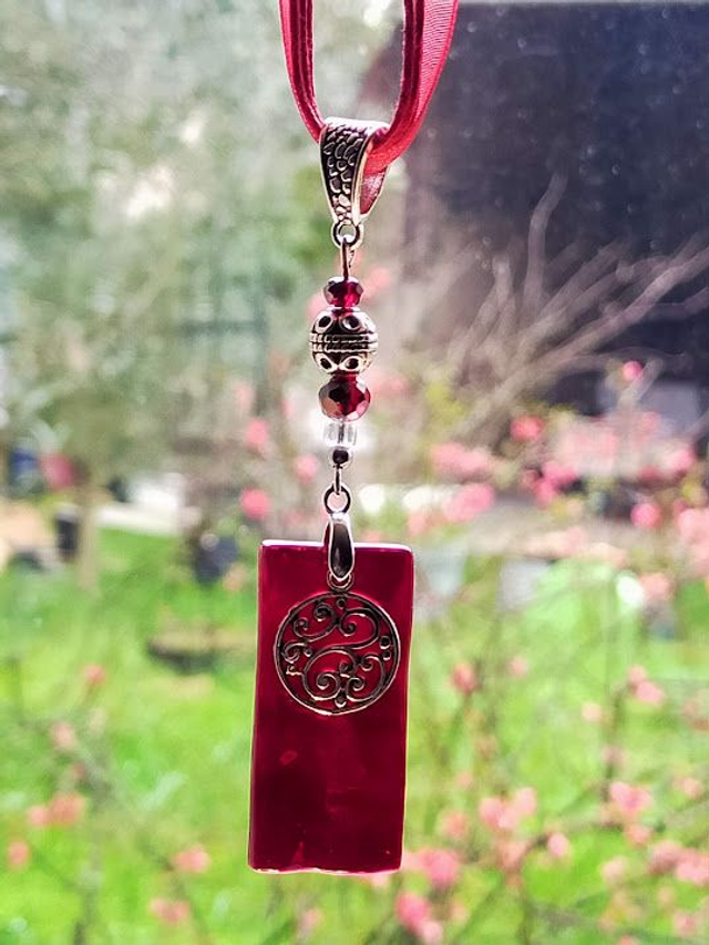 Pendentif en verre rouge cerise texturé et chaîne en coton rouge.