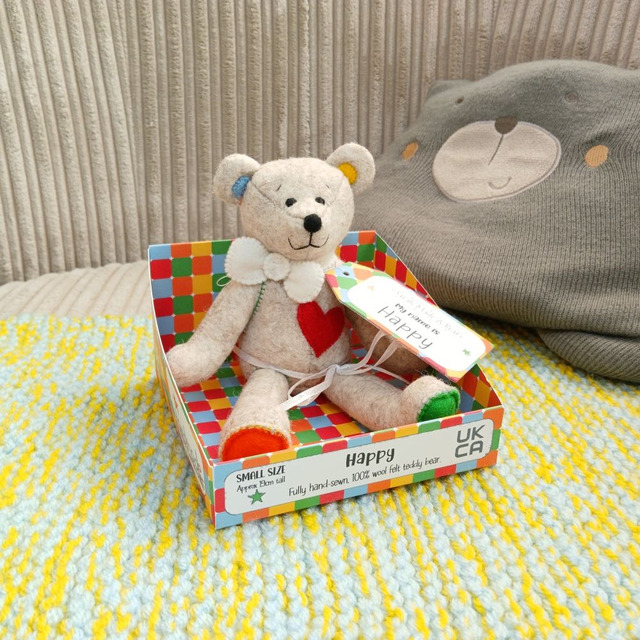 Happy. Small size, handmade teddy bear. UKCA. Tray base packaging. Standard Wool Felt. Beige. Bright rainbow. White. Blue. Green. Orange. Red. Yellow.