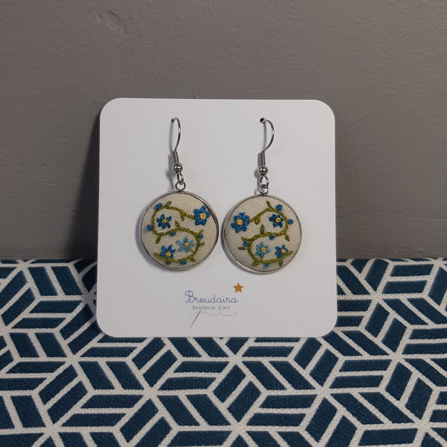 Boucles d&#039;oreilles fleurs bleues fond blanc