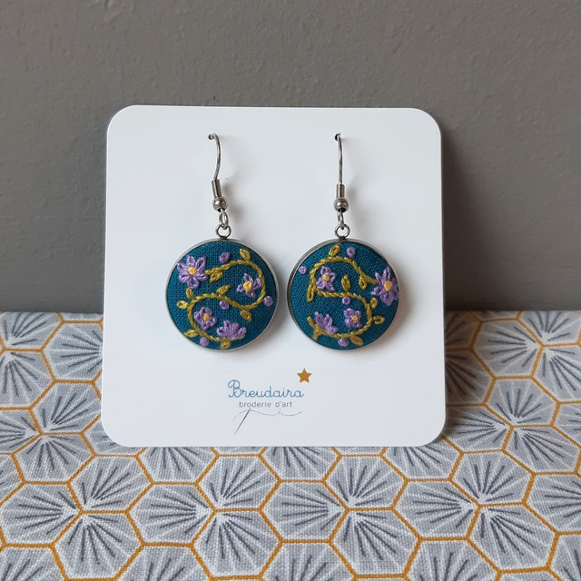 Boucles d&#039;oreilles fleurs mauves fond bleu