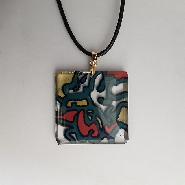 Pendentif carré collection vitrail fond transparent décor or rouge et bleu cerné de noir