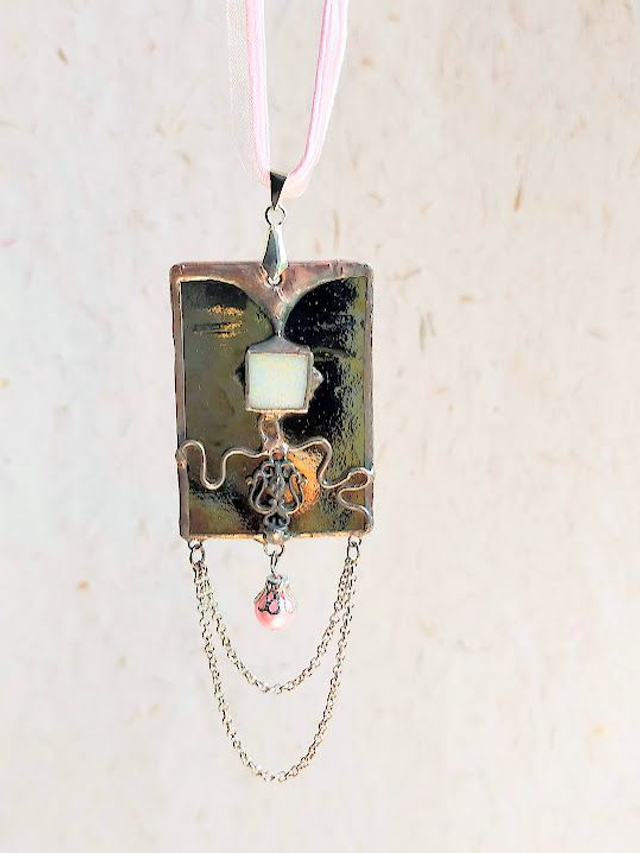Pendentif en verre doré et argent iridescent, sertis en Tiffany  et chaîne en coton ciré rose.