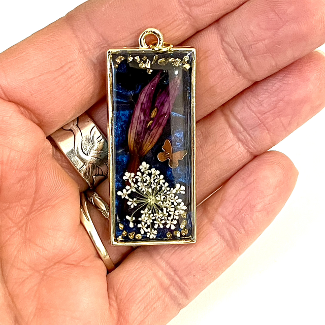 Médaillon doré rectangulaire avec insertion de fleurs naturelles et petits papillons doré et noir