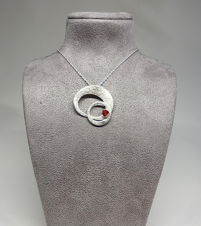 Orbital ring pendant with a deep orange cubic zirconia on silver necklace