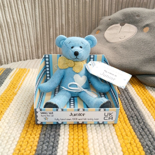 Junior. Small size, handmade teddy bear. UKCA. Tray base packaging. Standard Wool Felt. Blue. Yellow. White. Dark grey.