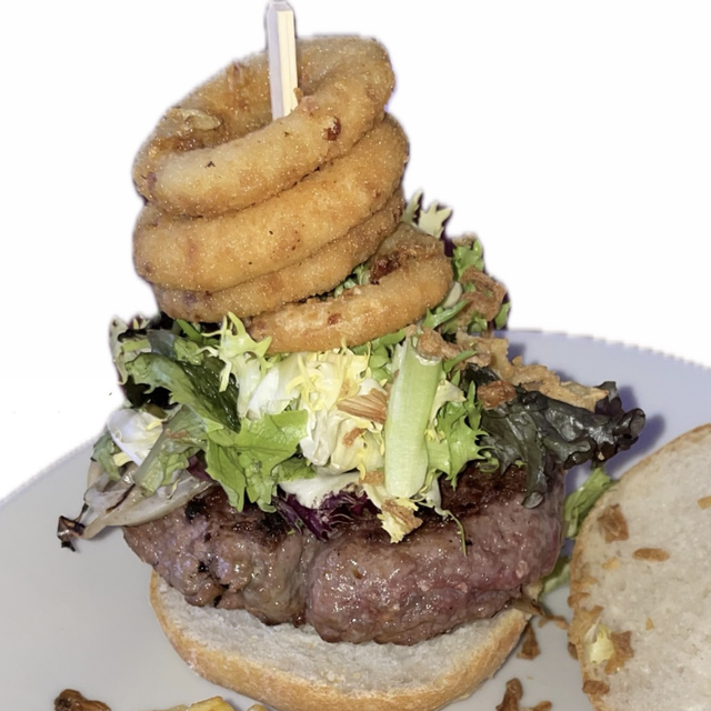 Hamburguesa de buey con cebolla caramelizada, aros de cebolla y patatas