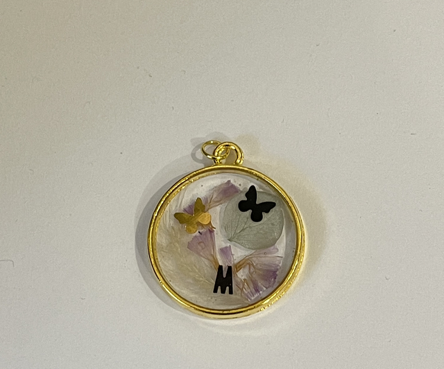 Pendentif rond doré avec incrustation lettre M, papillons et fleurs naturelles 